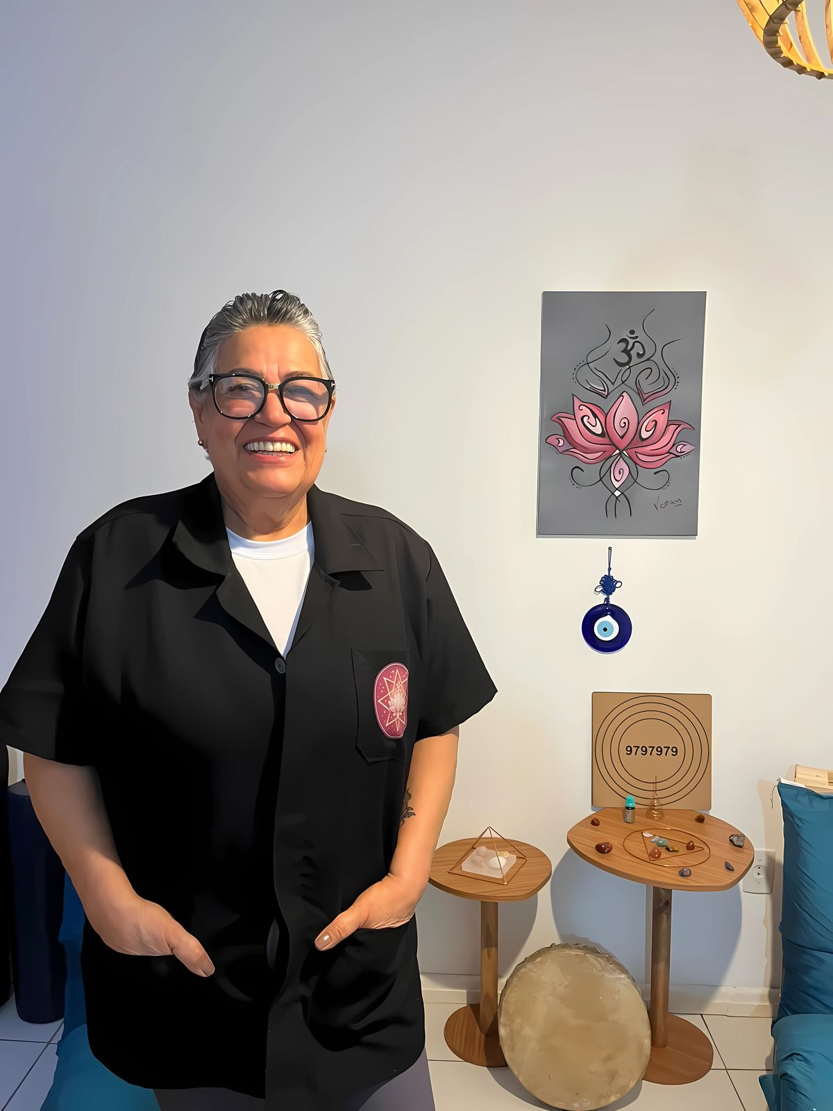 T. Beatriz L. Alves sorrindo no Studio Lótus, ao lado de um quadro de flor de lótus