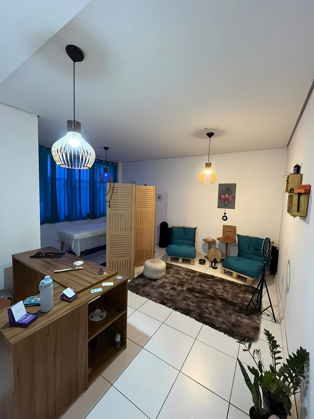 Ambiente do Studio Lótus: recepção, cantinho de meditação com almofadas e a sala da maca ao fundo
